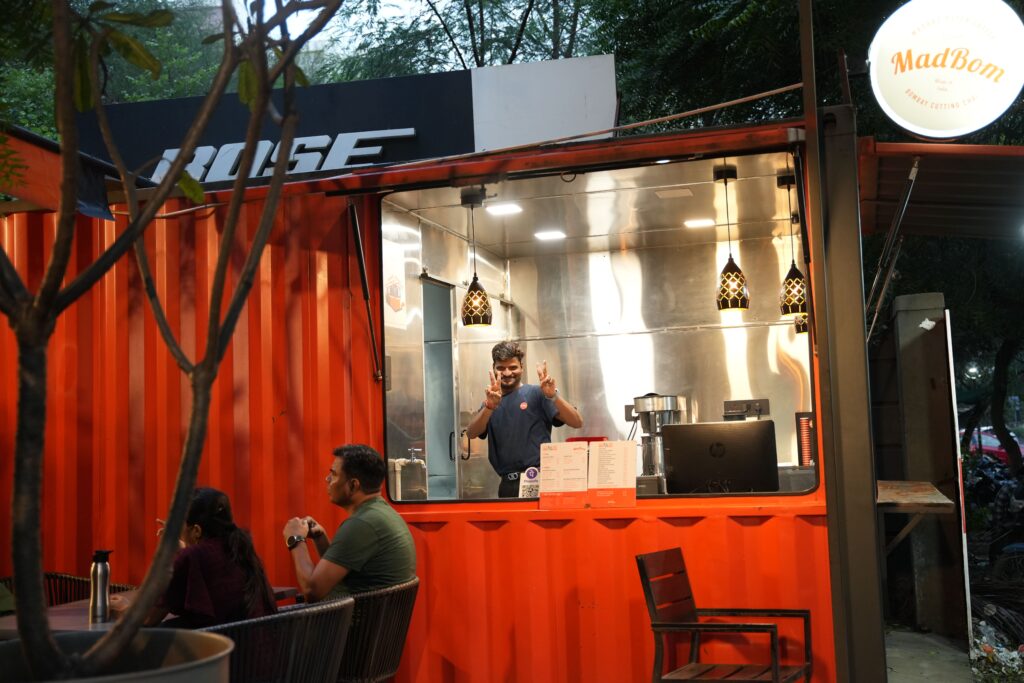 A man stands confidently in front of a restaurant, showcasing its inviting entrance and vibrant atmosphere.