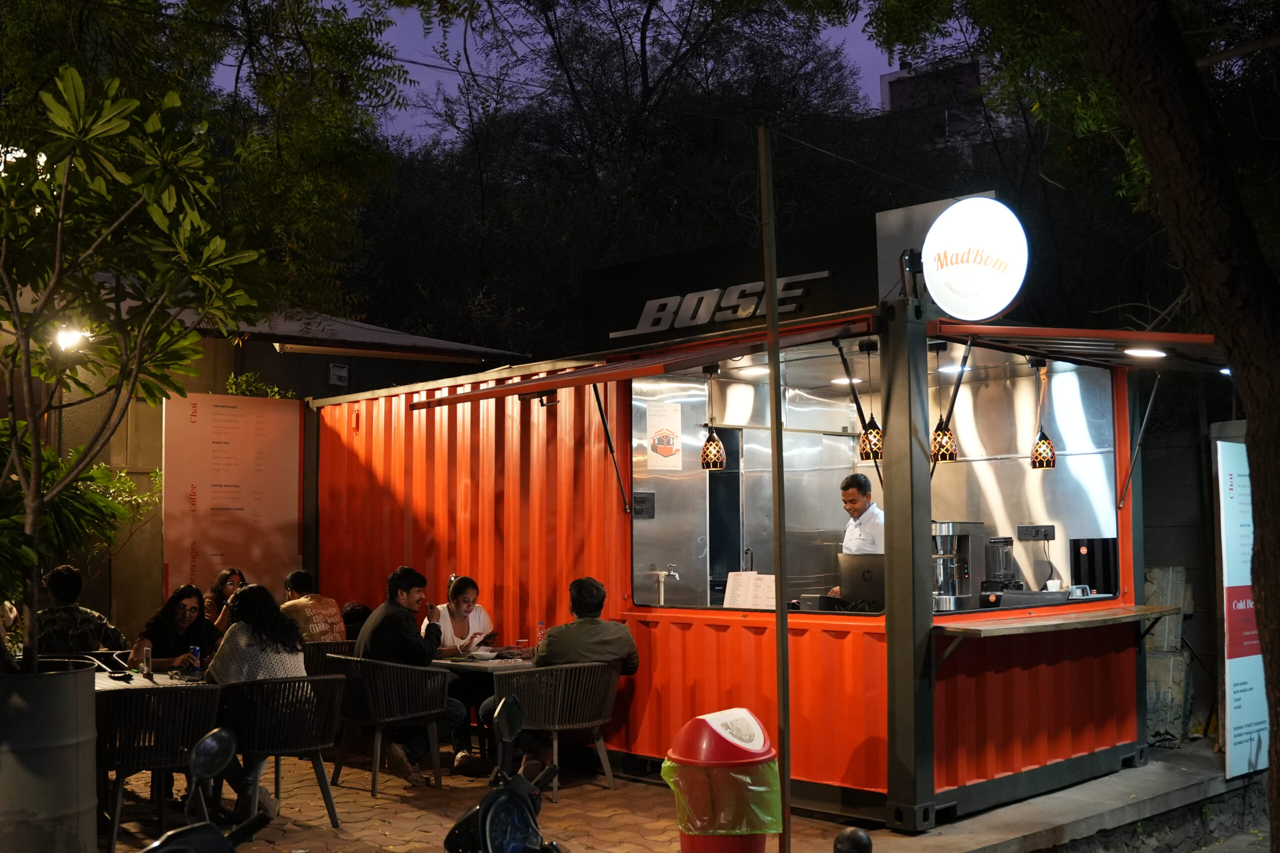 A lively restaurant scene at night, featuring patrons dining outdoors under soft lighting.